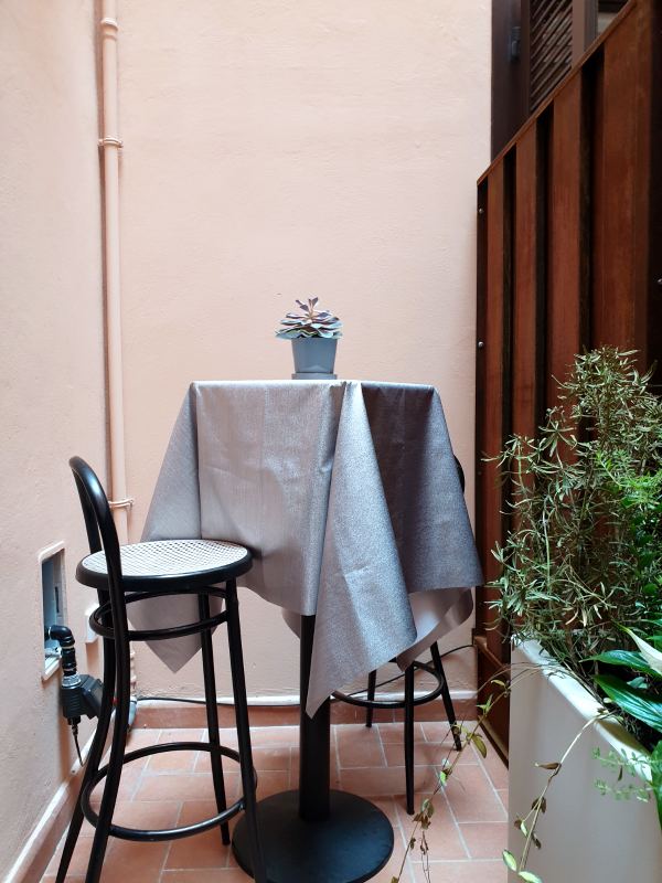 Small inner terrace with a tall bistro table, two stools and plants