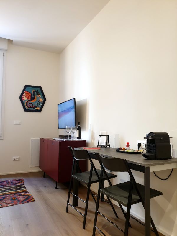 Dining table with two chairs, coffee machine, red sideboard and TV
